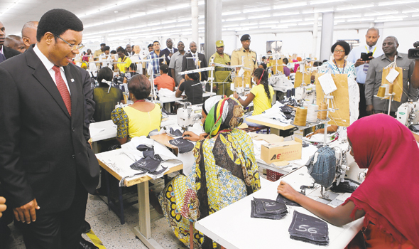 Prime Minister Kassim Majaliwa looks sewing process of jeans during visits Tanzania Tooku Garments Co. LTD at Export Processing Zones Authority (EPZA) in Dar es Salaam yesterday. PHOTO|PMO